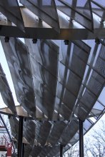 The woven wire mesh filters and reflects the light, giving the plaza a soft glow.